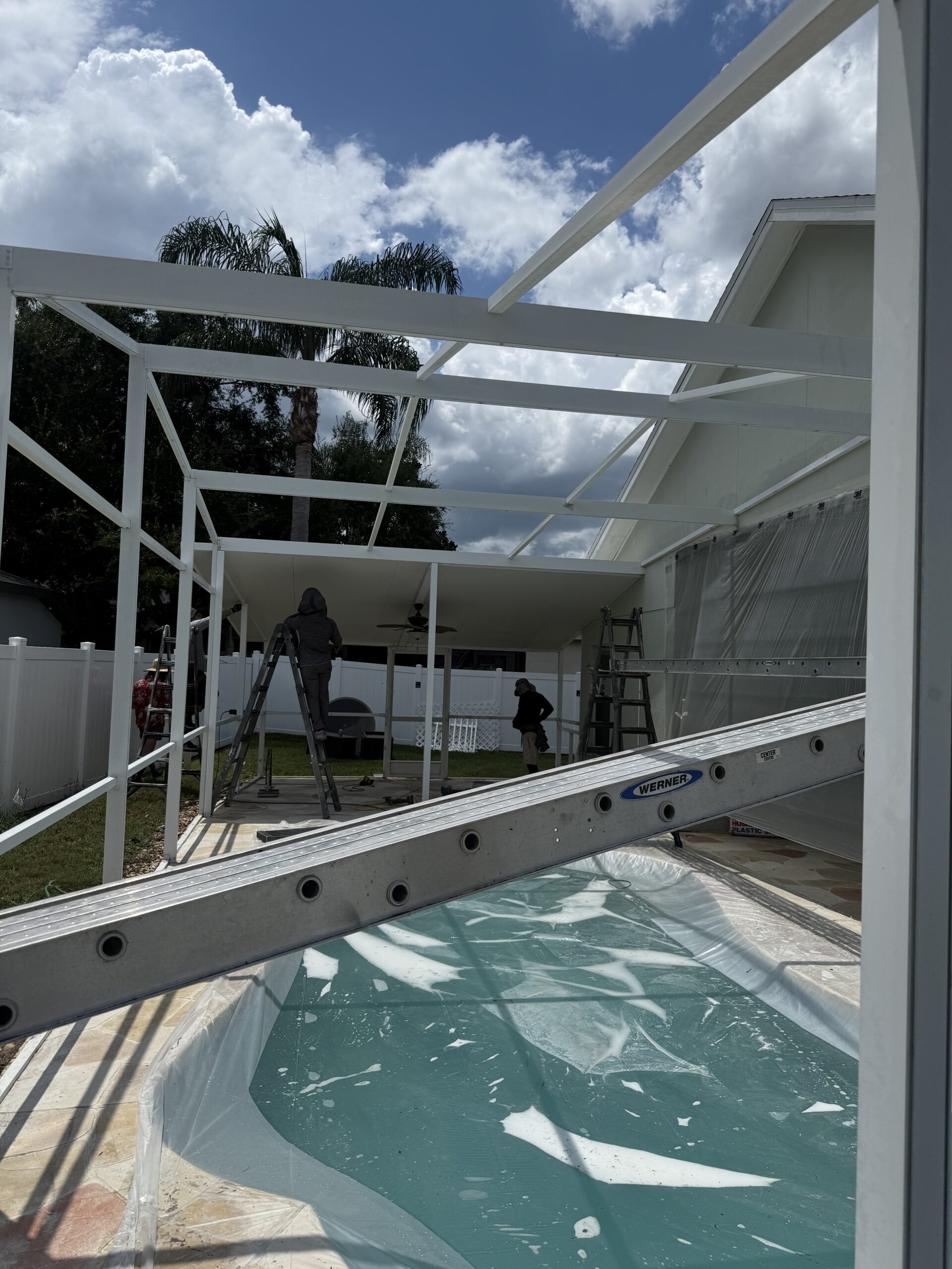 White pool cage before bronze painting restoration with deteriorated Tapcon anchors and screws